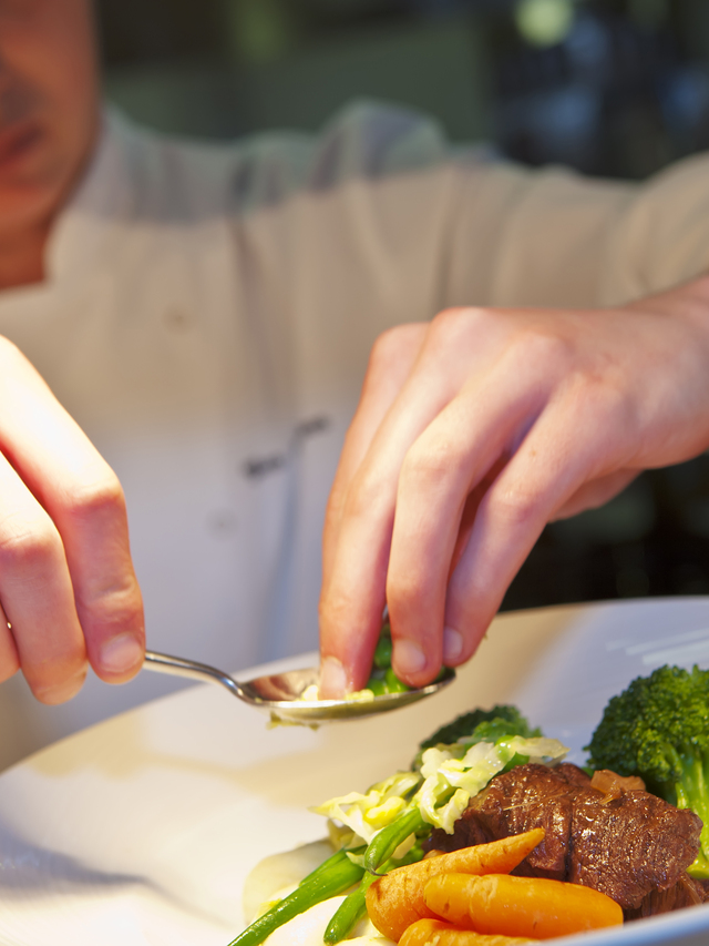 Closeup of chef adding finishing touch on his dish
